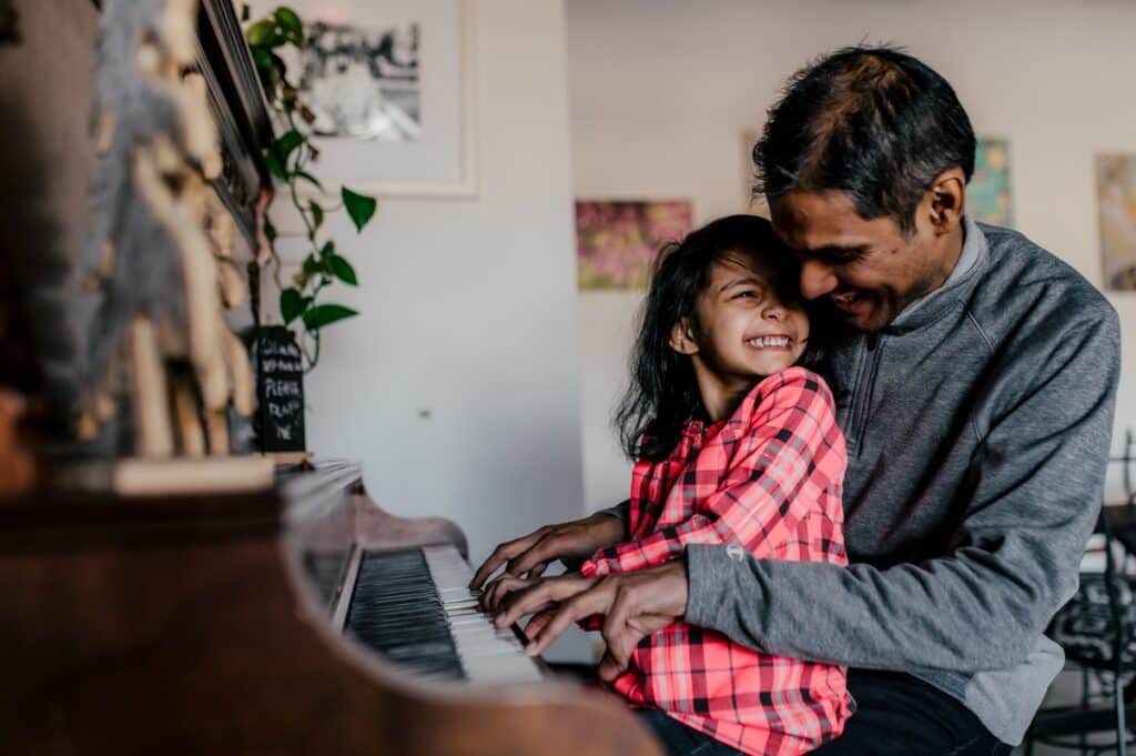 Man and child playing piano smiling