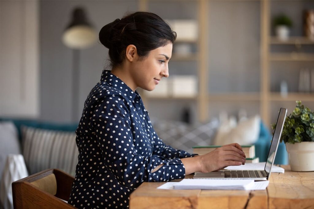 Woman sitting at desk typing on laptop