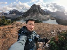 male traveler taking selfie portrait on the hill with mount assiniboine in national park at BC, Canada
