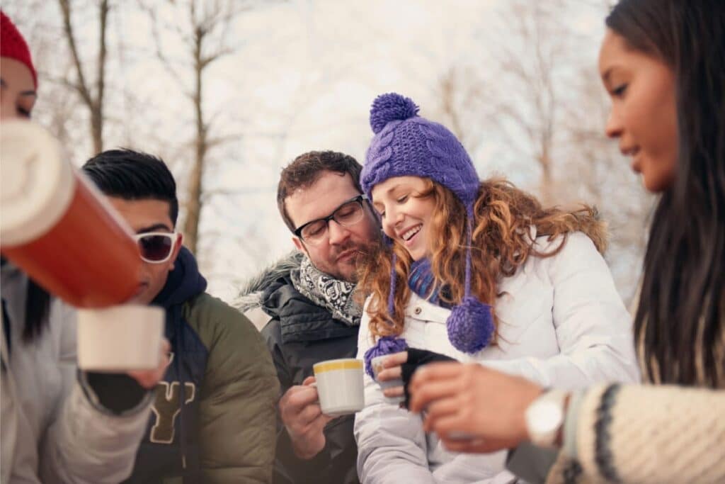 Group of millenial young adult friends enjoying wintertime and in a snow-filled park