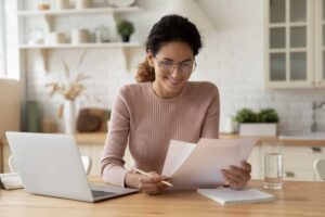 A young lady joyfully reviewing her documents at a table.