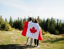 Couple with large Canadian flag celebration in mountains.