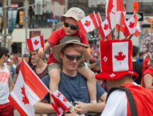 A father and son at a Canada day parade, surrounded by Canadian flags