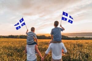 A family waving the Quebec provincial flag while standing in a field