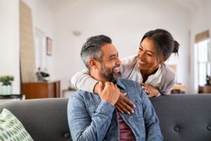 A couple being happy on the couch after applying for an Open Work Permit
