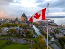 An overhead shot of Old Quebec, with the Canadian flag in the foreground and the St. Lawrence River in the background.