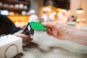 Man paying with debit card in cafe (1200x800)