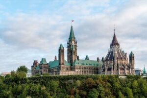 Parliament Hill in Ottawa, Ontario on a cloudy day, with some greenery visible.