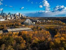 Panoramic aerial of Edmonton cityscape with bridges, river valley, and vibrant autumn colors.