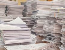 Very large stacks of papers atop a desk.