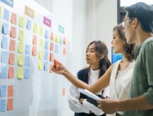 A trio of young people working on a flow board in their office.