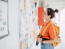An international student stares at a bulletin board with job postings