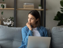 A woman sits pensively at her laptop