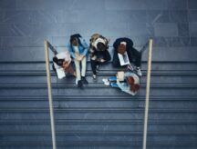 A group of students sit on the steps of their university campus.