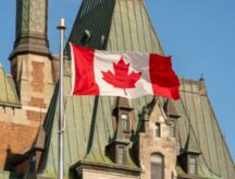 A picture of the Canadian flag against the back drop of parliament.