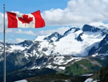 Canadian flag waving against the Rocky mountains in Whistler, Canada