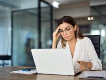 Person working at a laptop looking worried.