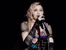 A shot of the American singer-songwriter Madonna performing during her 2015 Rebel Heart Tour, in which she is singing into a microphone.