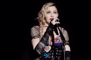 A shot of the American singer-songwriter Madonna performing during her 2015 Rebel Heart Tour, in which she is singing into a microphone.