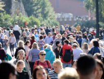 A large group of people walking on the street, heading in different directions.