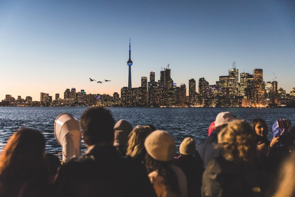 A group of people stare at the CN tower from across the lake.