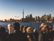 A group of people stare at the CN tower from across the lake.