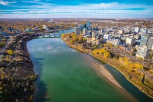 An aerial view of the Saskatoon's Central Business District, with a river, bridges, and variety of buildings visible.