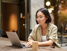 A person sitting at a cafe, while they complete the CV+ assessment form from their laptop