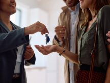 A real estate agent handing a couple the keys to their new home.