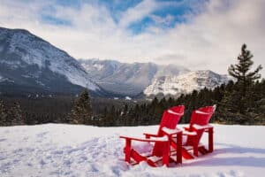 A pair of empty lawn chairs view the wide open mountain expanse.