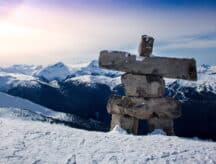 A sentry stands watch over a mountain range on a winter's day.