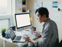 A young worker studies possible study programs on their work computer.