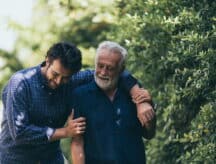 A man and his elderly father walking through a trail.