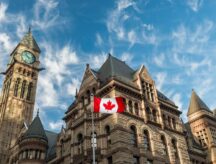 A Canadian flag waving in the wind in front of the Old City Hall in Toronto, Canada.