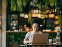 a woman sits at her laptop checking processing times.