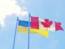 Ukraine and Canada, two flags waving against blue sky.