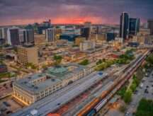 An aerial view of Winnipeg, Manitoba in the Summer—shot as the sun is setting, with buildings and roads visible.