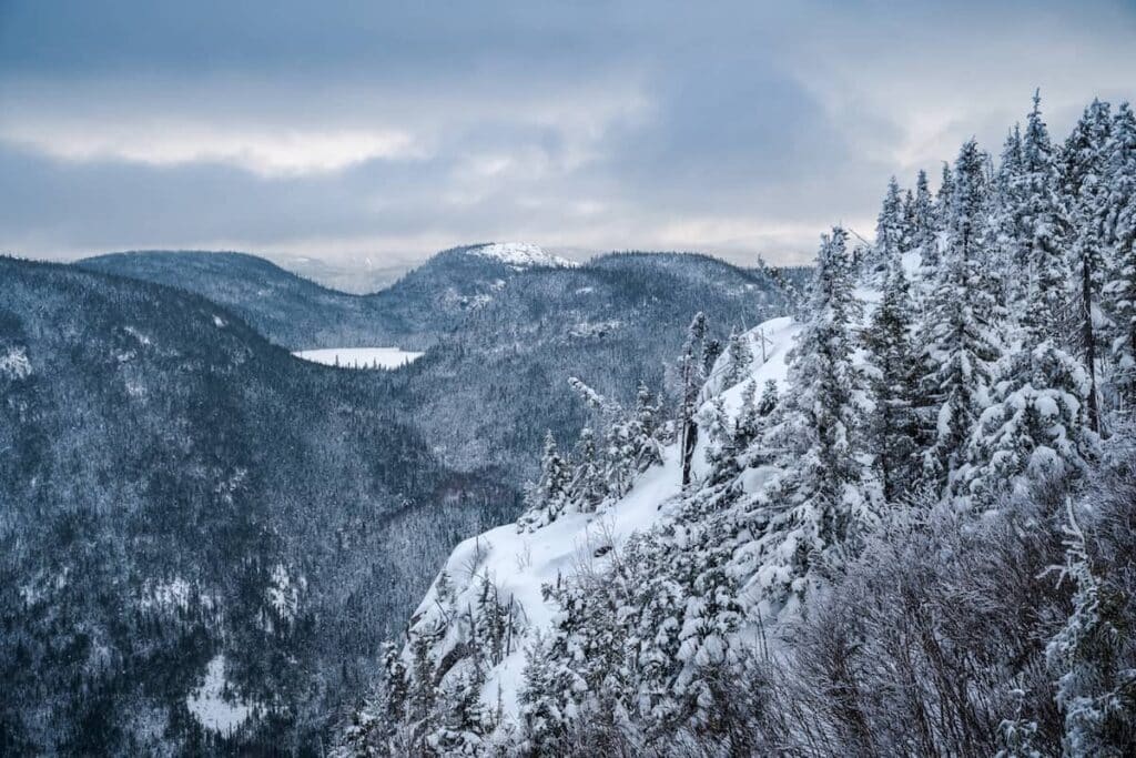 A winter mountainside with mountains in the background.