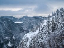 A winter mountainside with mountains in the background.