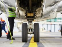 A group of aircraft inspectors look at an airplane preparing to take off.