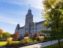 The Parliament Building in Quebec, Canada on a sunny day, with greenery around.