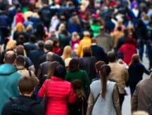A crowd of people walking on the street with their backs turned.