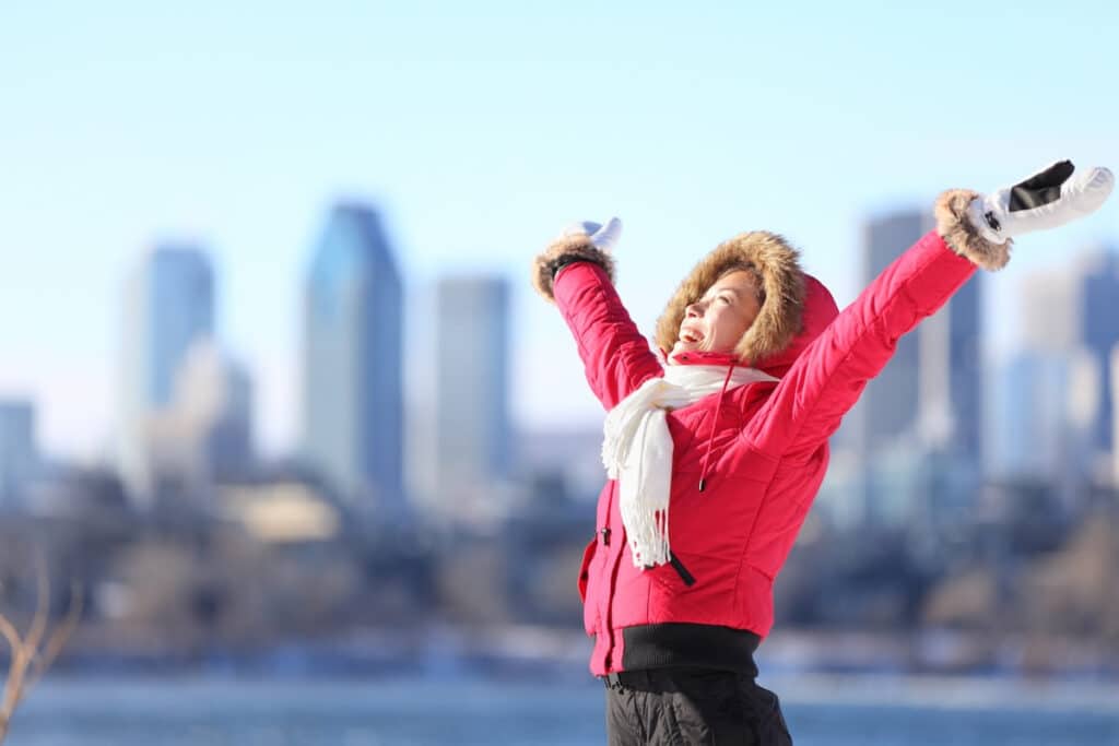 A woman smiles at the heavens with the Toronto skyline in the background