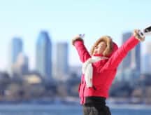 A woman smiles at the heavens with the Toronto skyline in the background