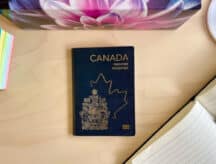 A picture of a Canadian passport on a desk, surrounded by office paraphernalia.