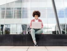 A person sitting outside on their laptop, applying for their SIN@Entry