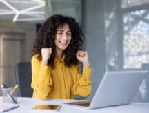 Young woman smiles in front of a laptop