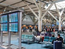 The inside of the Vancouver International Airport, with passengers awaiting boarding visible throughout.