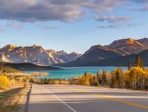 A view of a mountain, lake, and road in Alberta.