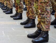 A group of new cadets line up outside a military base, close-up of their boots.